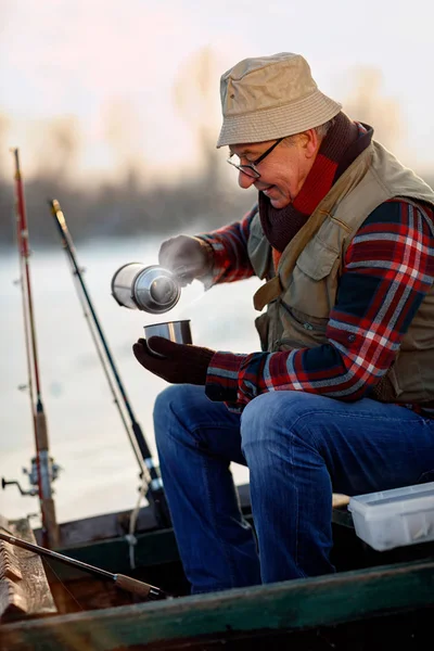 Pesca en hielo. hombre mayor sentado en el lago congelado y beber té —  Fotos de Stock