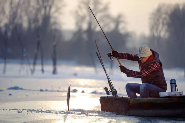 Pescador idoso pesca em lago congelado — Fotografia de Stock