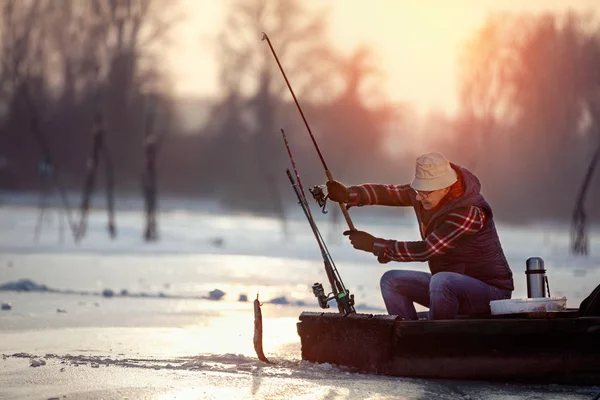 Pesca no gelo no lago congelado ao pôr do sol — Fotografia de Stock