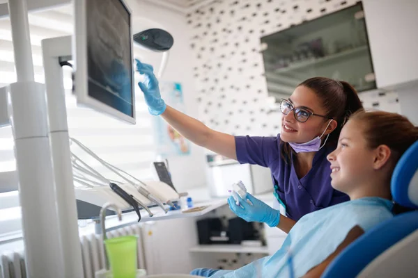 Tandarts met vrouwelijke jonge patiënt kijken haar tandheelkundige x-ray — Stockfoto
