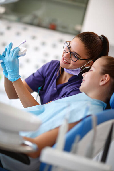 Child at dentist looking at model of jaw with teeth 