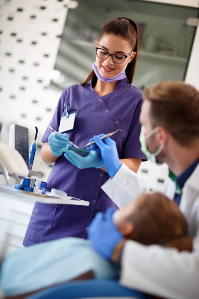 Dentista com enfermeira coloca preenchimento dentário — Fotografia de Stock