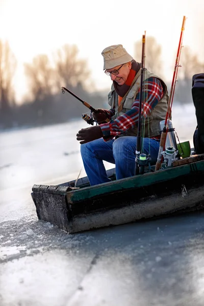 Pescador com vara de pesca sentar no rio congelado no inverno — Fotografia de Stock