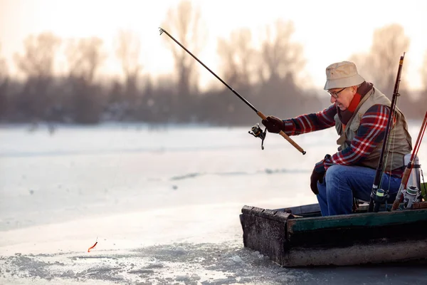 Homem idoso pesca no inverno no lago — Fotografia de Stock