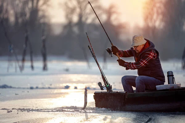 Рыбак рыбалка на льду на восходе солнца — стоковое фото