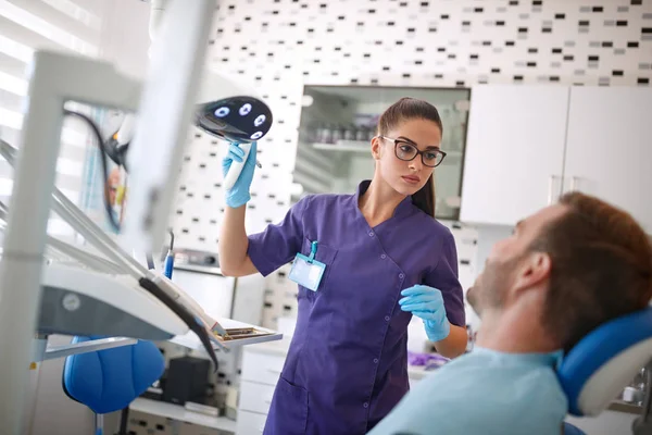 Стоматолог регулирует лампу отражателя перед восстановлением зубов — стоковое фото