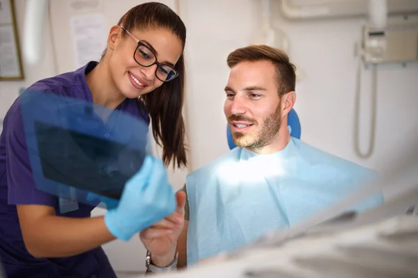 Dentista con paciente hablando sobre imágenes de rayos X dentales —  Fotos de Stock