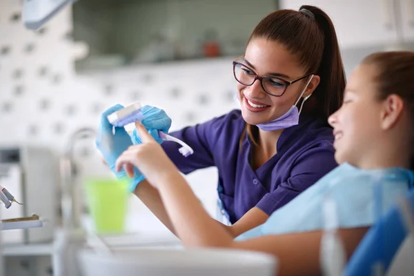 Dentista educa menina como escovar dentes — Fotografia de Stock