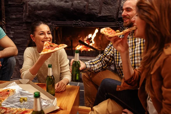 Amigos fazendo festa em casa enquanto brinda cerveja e comer pizz — Fotografia de Stock