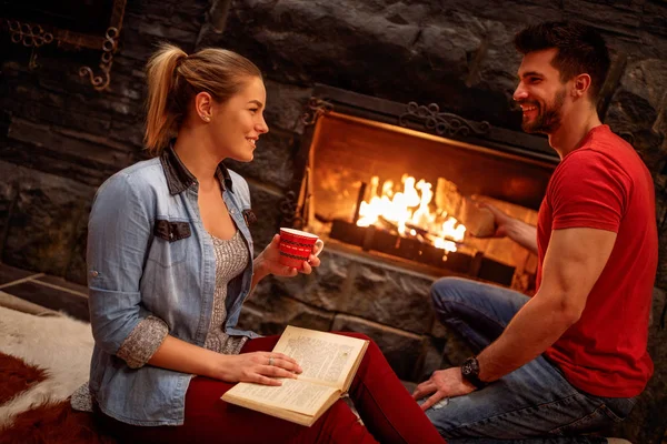 Smiling couple relaxing at home front of fireplace — Stock Photo, Image