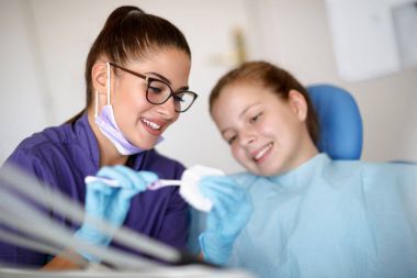 Dişçi kız için diş sandalyede düzgün metreyi fırça gösterilmiştir