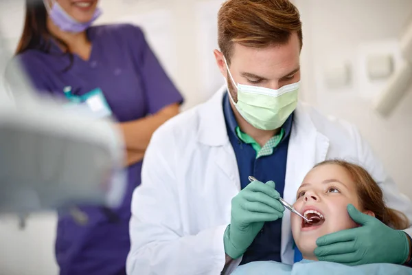 Odontólogo masculino examinando los dientes del niño con espejo dental — Foto de Stock