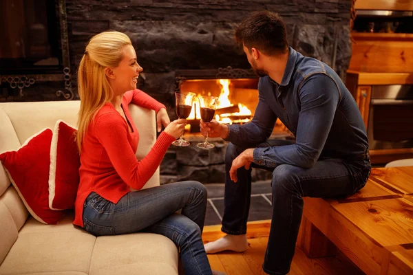 Casal apaixonado desfrutando no vinho perto da lareira — Fotografia de Stock