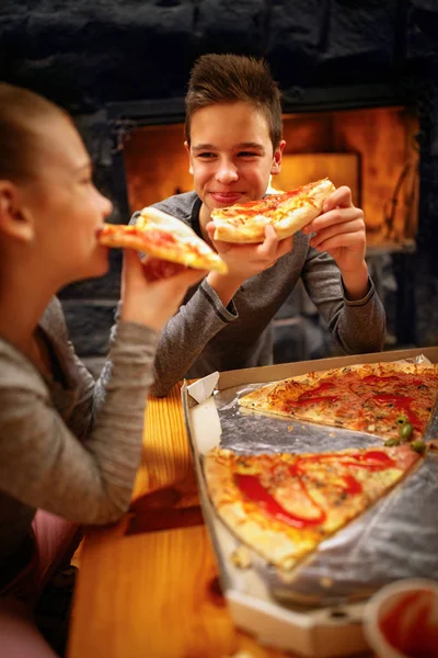 Uśmiechnięty chłopiec i jego siostra, jedzenie pizza plastry — Zdjęcie stockowe