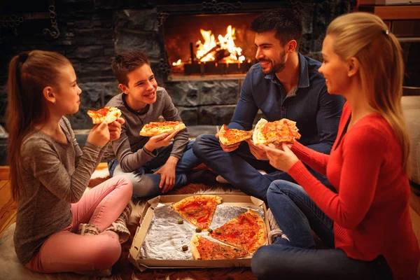 Улыбающиеся родители и дети едят пиццу на полу — стоковое фото