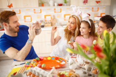 Yumurta boyama sırasında ailesine gülümseyen adam almak fotoğraf