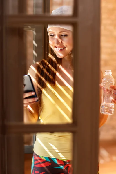 Mulher Feliz Olhando Telefone Celular Por Janela — Fotografia de Stock