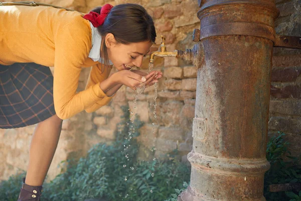 Молода дівчина п'є з питного фонтану — стокове фото