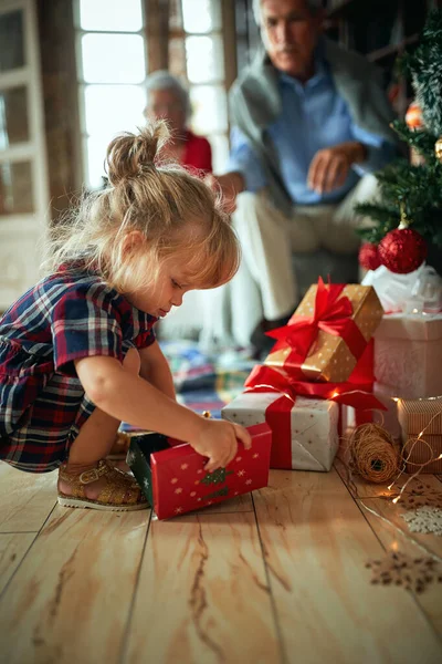 Chica abierta presente delante de un árbol de Navidad decorado — Foto de Stock