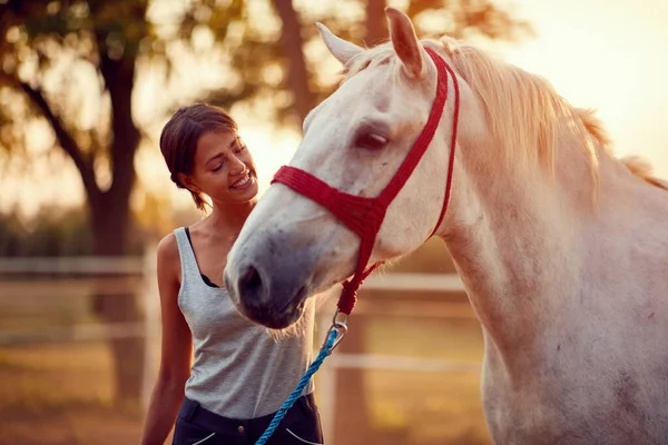 Donna sorridente accarezzare un cavallo in un ranch in una giornata estiva soleggiata . — Foto Stock