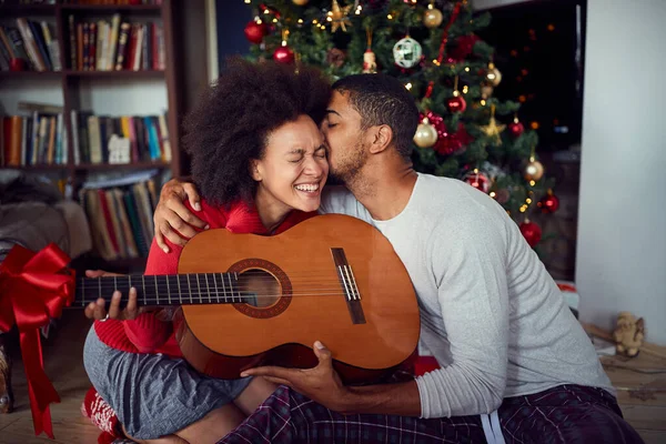 Family in front of decoration Christmas tree. man surprise woman a with a guitar gift for Christmas. — Stock Photo, Image