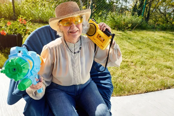 Modern Senior kvinna har roligt att leka med vattenpistol. — Stockfoto