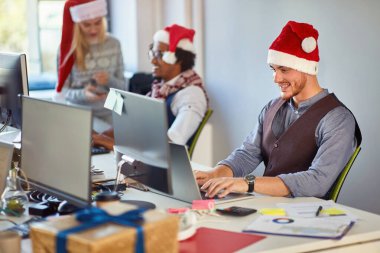 Genç işadamı Noel 'de ofiste bilgisayar başında çalışıyor..