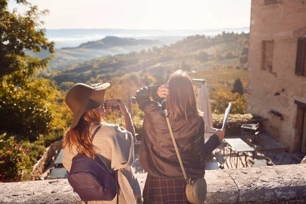 Vrouwen genieten van een zonnige dag op reis en maken foto 's op landsc — Stockfoto