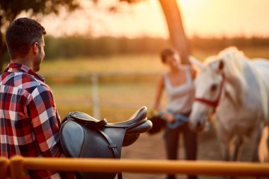 At eyeri tutan renkli tişörtlü bir adam.