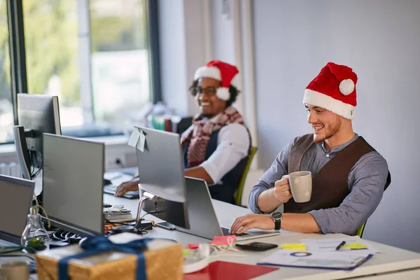 크리스마스에 산타 모자를 쓴 젊은 사업가가 컴퓨터로 일하는 모습 — 스톡 사진