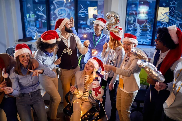 Glückliche Geschäftsleute in Weihnachtsmänteln feiern Feiertag bei der Arbeit. — Stockfoto