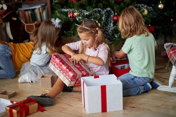 Kids opening Xmas presents. Children under Christmas tree with g