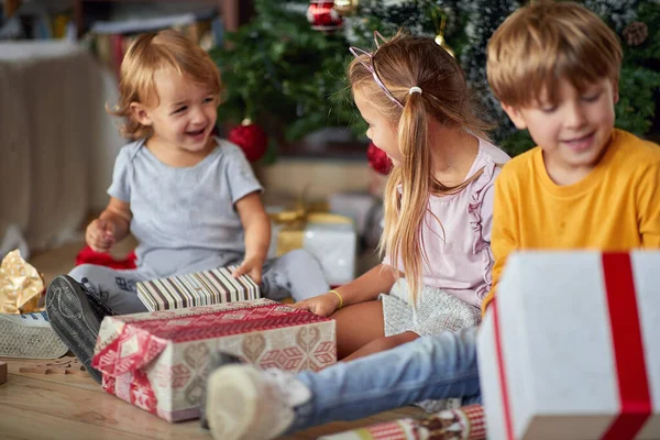 Bonito crianças abrindo presente de Natal em casa . — Fotografia de Stock