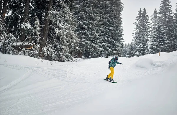 Young snowboarder snowboarding in mountain — Stock Photo, Image