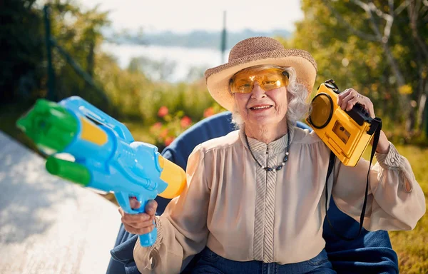 Galen senior kvinna på semester leker med vattenpistol — Stockfoto