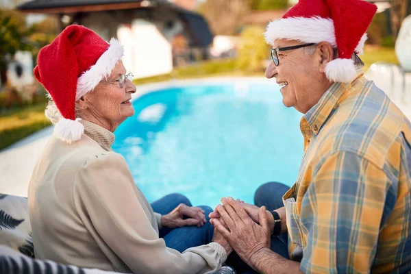 Χαρούμενο ηλικιωμένο ζευγάρι σε Σάντα καπέλα γιορτάζει τα Χριστούγεννα — Φωτογραφία Αρχείου