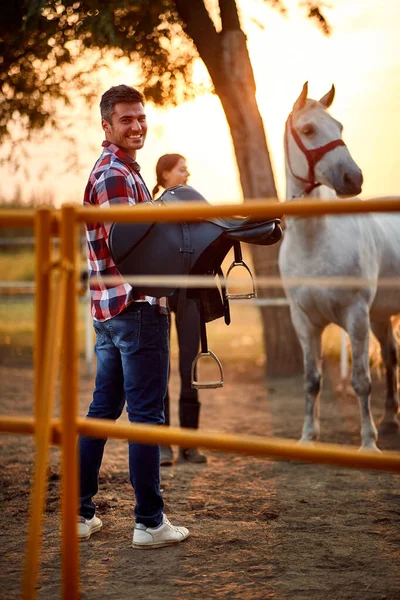 Smiling man carrying a horse saddle — Stock Photo, Image