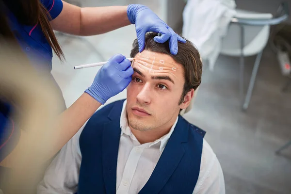 Man met markeringen op het gezicht voor het verbeteren van schoonheid en corrigeren van de — Stockfoto