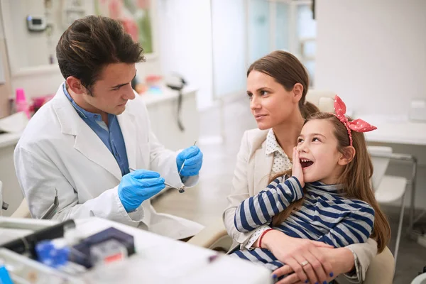 Rodzina w gabinecie dentystycznym.Dziewczyna cierpiąca na ból zęba — Zdjęcie stockowe