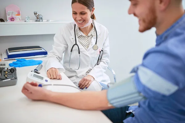 Sorridente medico sta controllando la pressione sanguigna del paziente . — Foto Stock