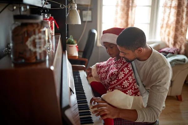 Noel, kış tatili, yeni yıl partisi ve aile kavramı. Baba ve çocuk piyanoda müzik çalıyorlar.. — Stok fotoğraf