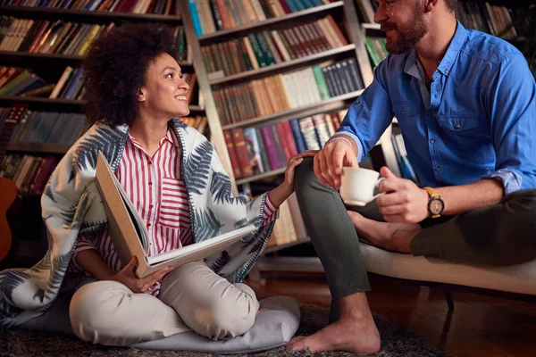 Romantiskt par njuter hemma och läser en bok. — Stockfoto