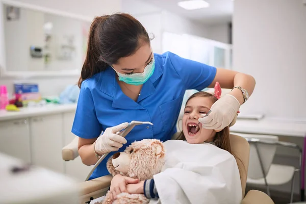 Mujer dentista examinando paciente dental en procedimiento dental . —  Fotos de Stock