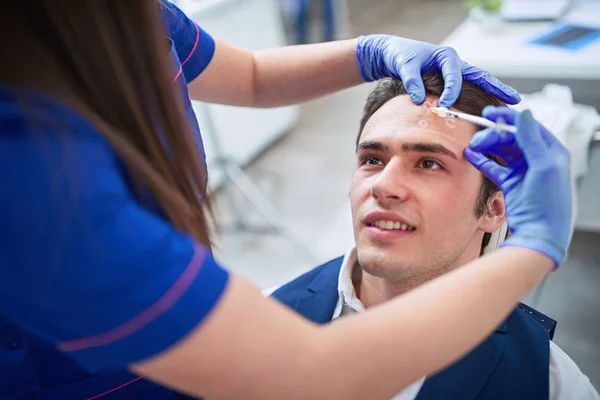 Az arcon látható jelölésekkel rendelkező férfi fiatalító arcinjekciót kap — Stock Fotó