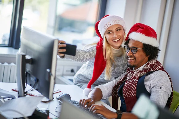 Erkek ve kadın Xmas 'ta çalışıp Noel Baba şapkasıyla selfie çekiyorlar. — Stok fotoğraf