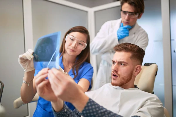 Patiënt met werkende mensen op zoek naar röntgenfoto van tanden — Stockfoto