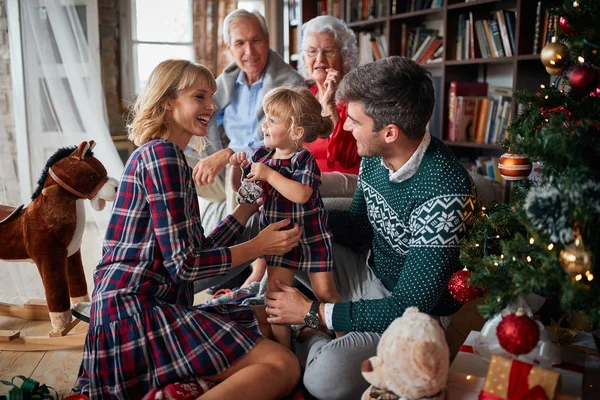 Gelukkig gezin zittend naast een kerstboom — Stockfoto