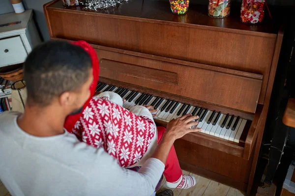 Meisje en vader spelen samen muziek aan de piano op eerste kerstdag. — Stockfoto