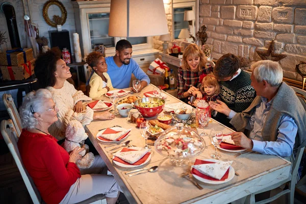 Vrienden en families aan een kersttafel — Stockfoto