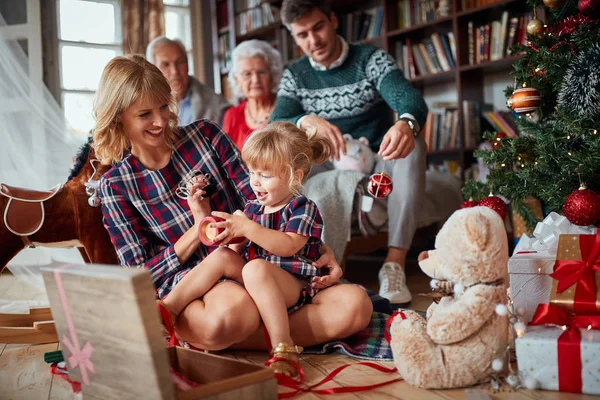 Pečující matka učí své dítě zdobit vánoční stromek — Stock fotografie